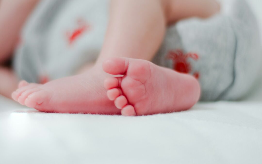 bebé con pañal blanco mostrando el pie